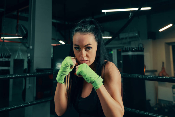 Femme athlétique debout préparée au combat avec des bandages de boxe sur les mains pendant l'entraînement en boîte
 - Photo, image