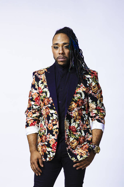 Studio portrait of a man wearing a flower patterned suit and dreadlocks - Photo, Image