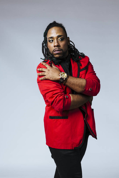 Closeup studio portrait of a man wearing a red jacket suit and dreadlocks - Photo, image