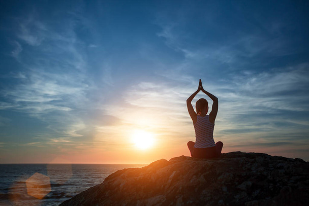 Yoga Silhouette Frau meditiert am Strand des Ozeans bei atemberaubendem Sonnenuntergang.  - Foto, Bild
