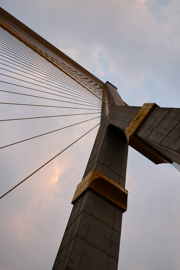 Pylon i metalowe kable ogromnego mostu wiszącego na niebie. - Zdjęcie, obraz