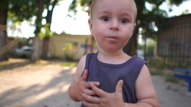 Un garçon de deux ans avec les cheveux blancs court autour de la caméra sur le terrain de jeu et tente de l'attraper
 - Séquence, vidéo