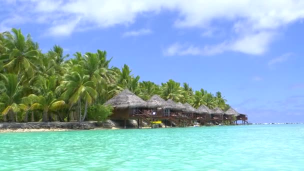 perfect holiday destination with glassy ocean water glistens in the bright summer sunshine near breathtaking tropical island with bungalows - Footage, Video