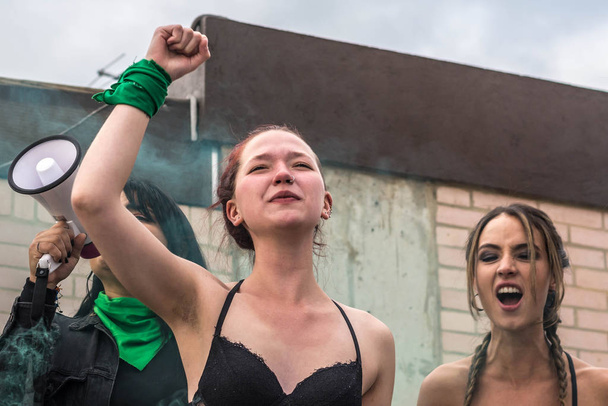 Feministengruppe mit erhobenen Fäusten und Megafon-Lautsprechern umgeben von grünem Rauch - Foto, Bild