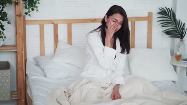 Woman just woke up, sits on bed, yawning, frustrated that she needed to get up - Imágenes, Vídeo