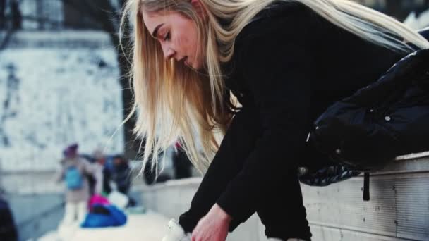 Uma jovem loira amarra seus patins antes de sair na pista
 - Filmagem, Vídeo