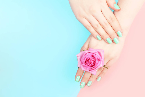 Női kéz menta színű manikűr rózsaszín és kék háttér másolási hely, felső nézet - Fotó, kép