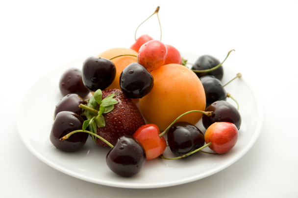 Apricots, strawberry and cherries on the plate - Photo, image