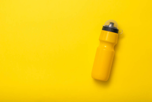 Botella de agua deportiva amarilla sobre fondo amarillo. Puesta plana
. - Foto, Imagen