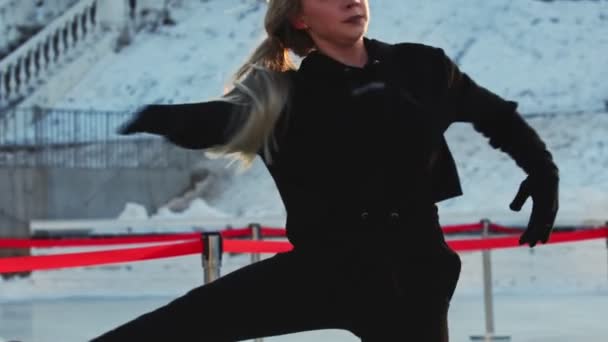 Een jonge vrouw figuur schaatser draaien rond zichzelf op de ijsbaan buiten - Video