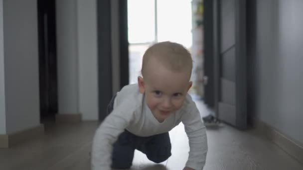 Šťastný chlapeček se plazí ke kameře na dřevěné podlaze. Gimbalův pohyb - Záběry, video