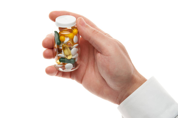 Чоловік рука зі скляною пляшкою, повна таблеток, таблеток, вітамінів, ліків, капсул ізольовані на білому тлі. Біла сорочка, бізнес-стиль. Концепція охорони здоров'я. Фармацевтична промисловість. Аптека
. - Фото, зображення