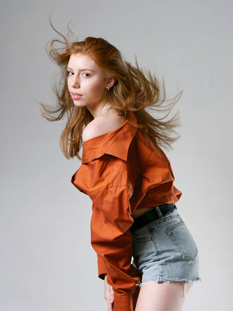 jovem com longos cabelos vermelhos em um fundo cinza
 - Foto, Imagem