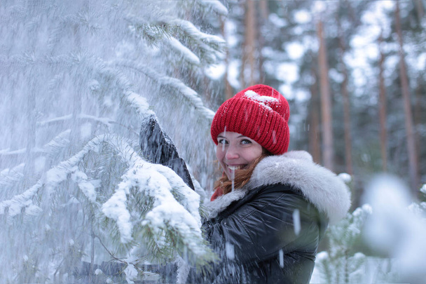 Piękna atrakcyjna dziewczyna z zielonymi oczami i rudymi włosami spaceruje w zimowym lesie w dobrym nastroju - Zdjęcie, obraz