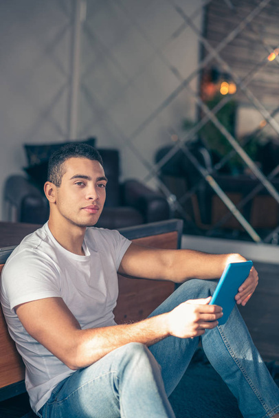 Handsome guy sitting on the floor thinking with a tablet. - Foto, immagini