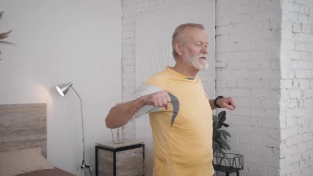oude knappe man leidt een gezonde levensstijl en doet nuttige oefeningen voor gezondheid en vitaliteit in ruimte met een creatief interieur - Video