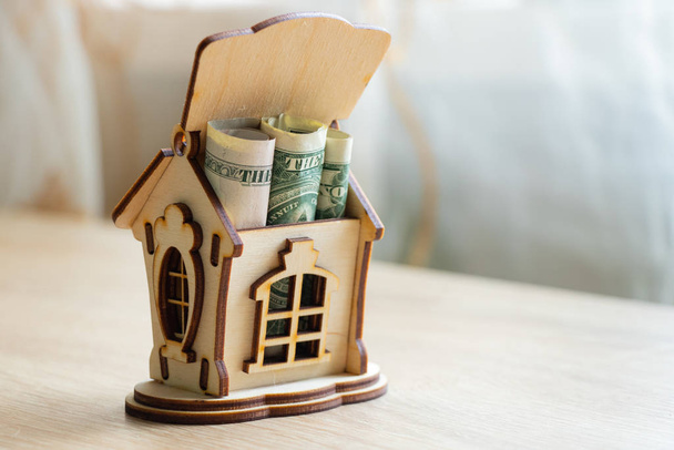 drewniany dom z pieniędzmi na stole stoi w pokoju - Zdjęcie, obraz