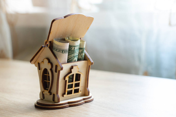 la casa di legno con soldi i dollari su un tavolo sta in una camera
 - Foto, immagini