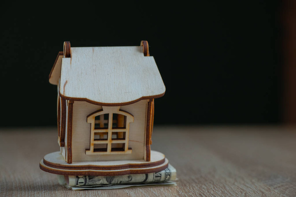 Holzhaus mit Geld Dollar auf einem Tisch steht in einem Raum - Foto, Bild