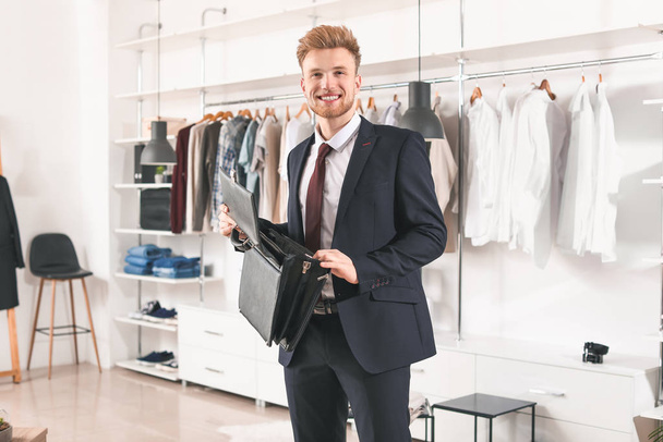 Handsome man choosing briefcase in dressing room - Photo, Image