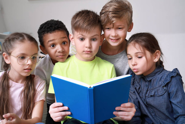 Surprised little children reading book indoors - 写真・画像
