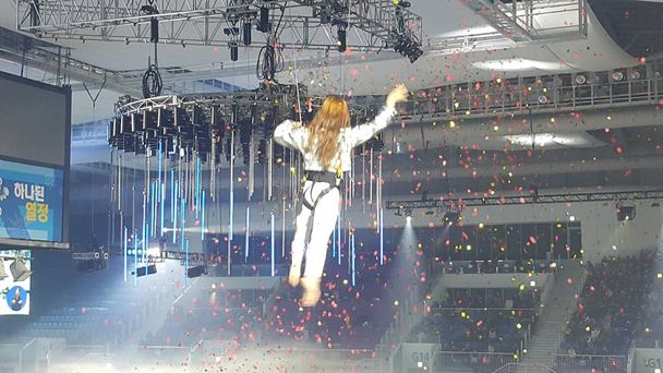 Молода дівчина виконує акробатичні елементи у повітряному кільці під час фестивалю "Пхенчхан знову" на стадіоні "Льодова Арена". - Фото, зображення