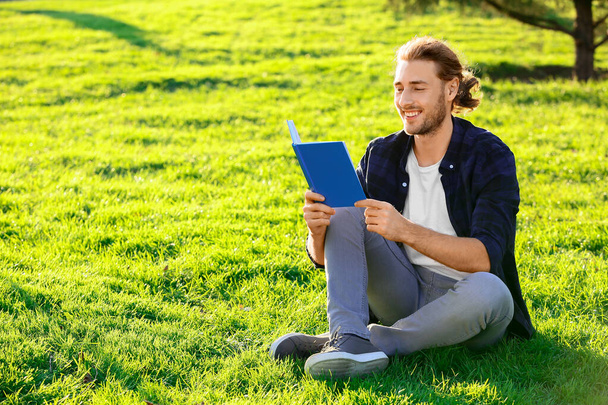 Handsome man reading book outdoors - Foto, imagen