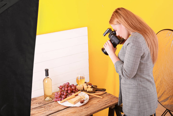 若い女性はプロのスタジオでチーズとワインの写真を撮る - 写真・画像