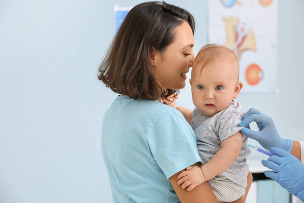 診療所で小さな赤ちゃんをワクチン接種する小児科医 - 写真・画像