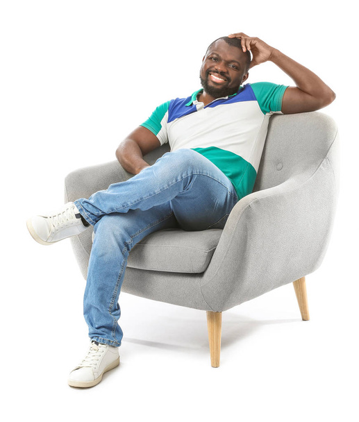 Hombre afroamericano relajándose en sillón sobre fondo blanco
 - Foto, imagen