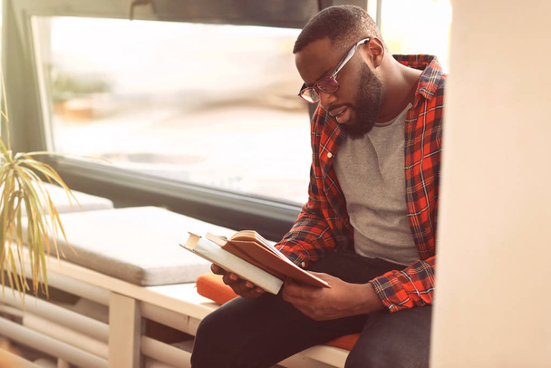 Estudiante afroamericano leyendo libro mientras se prepara para el examen en la biblioteca
 - Foto, imagen