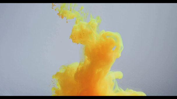 slow motion of flowing abstract yellow paint cloud on grey background - 映像、動画