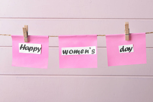 Ευχετήριες κάρτες για την Παγκόσμια Ημέρα της Γυναίκας κρεμασμένες σε σχοινί σε λευκό ξύλινο φόντο - Φωτογραφία, εικόνα
