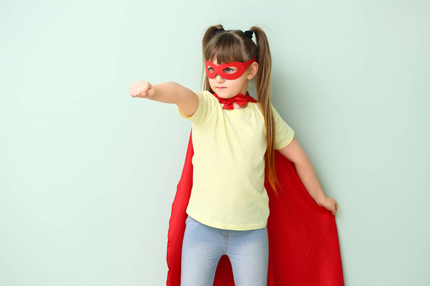 Little girl in superhero costume on color background. Concept of feminism - Foto, Imagem