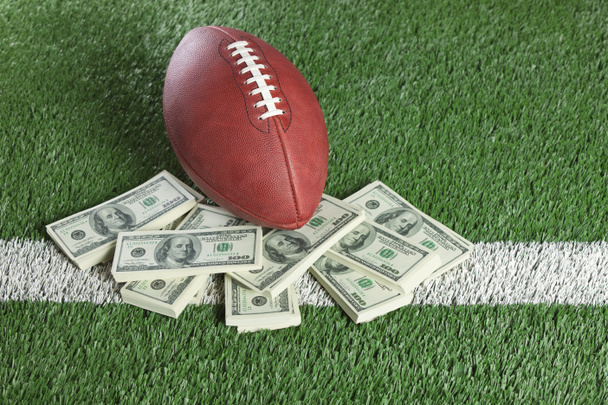 NFL football on field with a pile of money - Фото, зображення