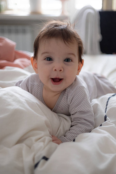 Little cute infant baby portrait in gender neutral clothes smiling - Fotó, kép