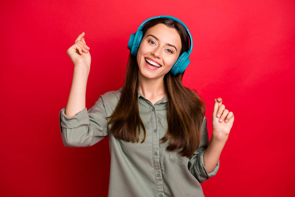Photo of attractive lady cheerful mood modern technology headphones on ears listen new popular youth song wear casual grey green shirt isolated red color background - Foto, Imagem
