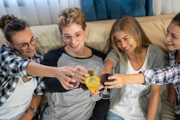 Деталь рук групи молодих людей з тостами для окулярів, що сидять на дивані - Фото, зображення