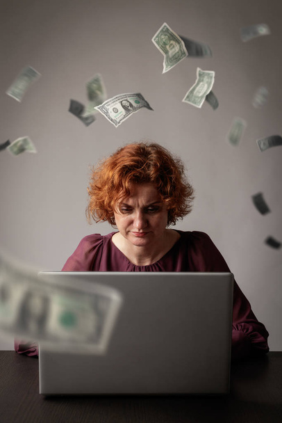 Red-haired woman with laptop. Red-haired woman and falling dolla - Fotó, kép