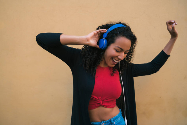 Young afro woman listening to music with headphones. - Φωτογραφία, εικόνα