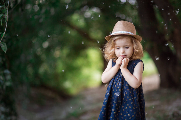 girl in a straw hat looks at poplar fluff - Фото, изображение