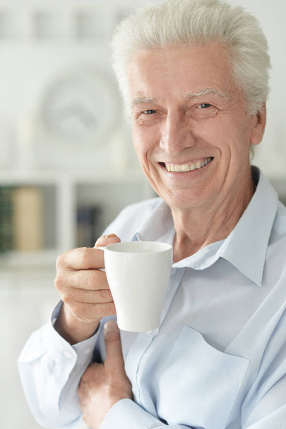 Portrait of smiling senior man drinking coffee  at home  - Zdjęcie, obraz