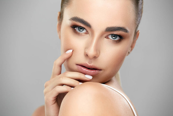 close-up of elegant woman with strong grey eyes and brown make-up looking to camera on grey background - Photo, Image