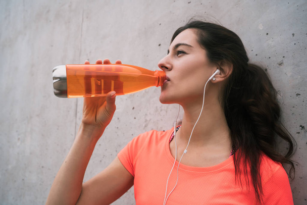 Athletic woman drinking water after training. - Foto, imagen