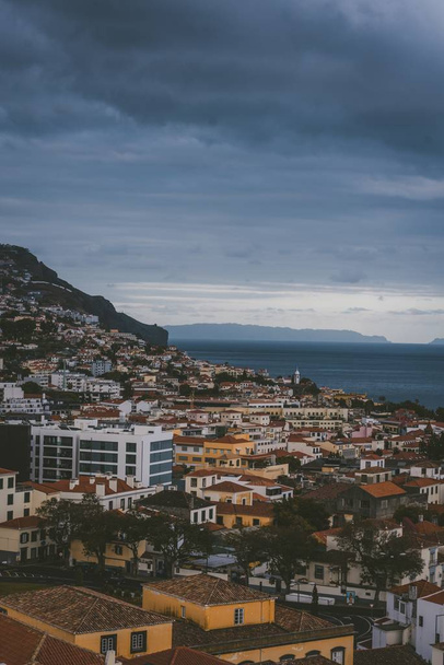 Függőleges felvétel épületekről a hegyen felhős ég alatt Funchal, Madeira, Portugália. - Fotó, kép