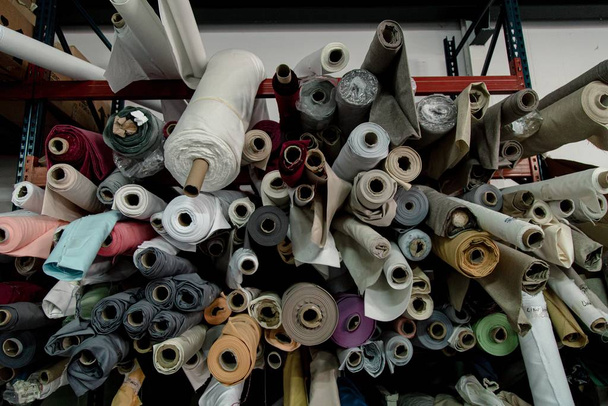 A lot of colorful textile rolls in a textile factory - 写真・画像