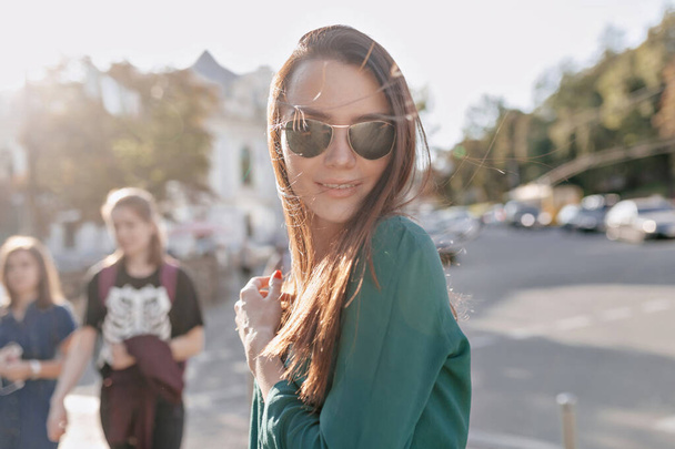 Schattige mooie vrouw met een vrolijke glimlach wandelen in de zon op de stad en genieten van een goede warme dag - Foto, afbeelding
