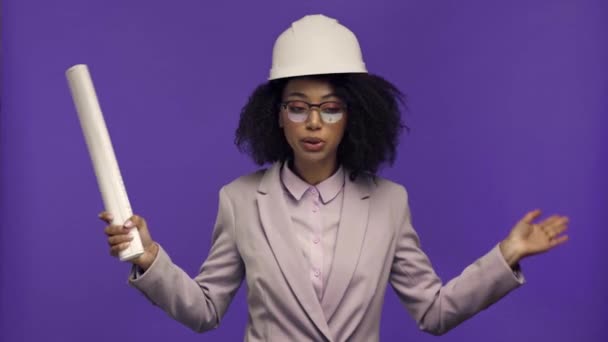 Irritierter afrikanisch-amerikanischer Ingenieur zeigt Blaupause isoliert auf violett  - Filmmaterial, Video