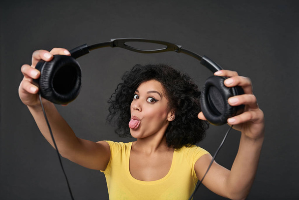 Excited woman giving you headphones, studio shot - Foto, imagen