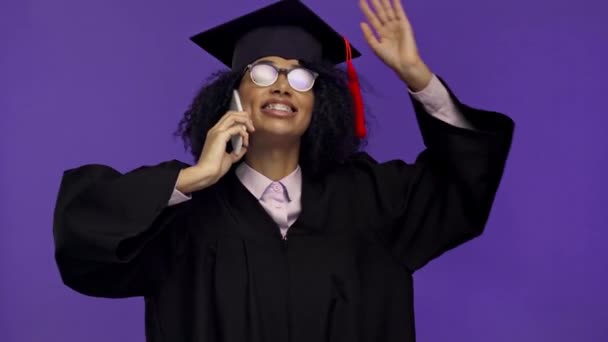 glimlachen Afrikaans amerikaanse afgestudeerde praten op smartphone geïsoleerd op paars  - Video